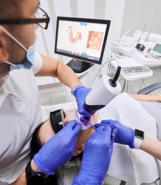 Modern high precision technologies in dentistry Dentist and his assistant scanning patient's teeth with modern scanning machine. Digital print of patient's teeth is on big screen. Modern high precision technologies. Concept of modern dentistry