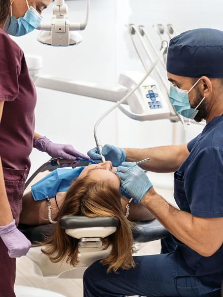 Young Girl Patient in Dentist Stock photo of workers of a dental clinic wearing uniforms with a patient during a checkup.