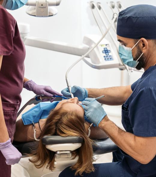 Stock photo of workers of a dental clinic wearing uniforms with a patient during a checkup.